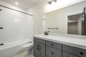 Full bathroom with tiled shower / bath, vanity, toilet, and tile patterned floors