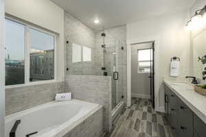 Bathroom with vanity, a textured ceiling, wood-type flooring, and independent shower and bath