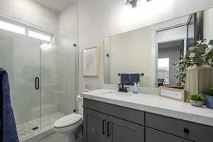 Bathroom with a shower with door, vanity, and toilet