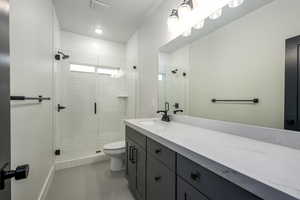 Bathroom with vanity, toilet, tile patterned floors, and a shower with shower door