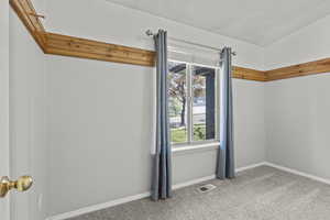 Carpeted empty room with visible vents and baseboards