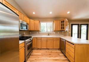 Kitchen with light hardwood / wood-style floors, appliances with stainless steel finishes, sink, and kitchen peninsula