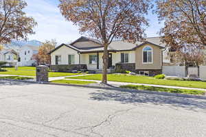 View of front facade featuring board and batten siding, fence, stone siding, and a front yard