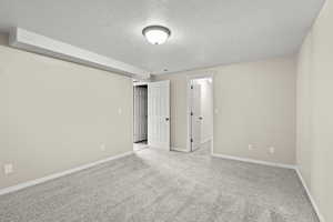 Unfurnished bedroom with a textured ceiling, baseboards, and carpet