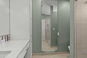 Bathroom with vanity, baseboards, toilet, and a shower stall