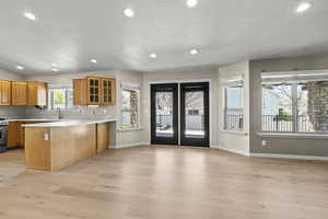 Kitchen featuring a sink, light countertops, light wood finished floors, a peninsula, and glass insert cabinets