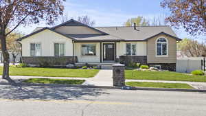 View of front facade featuring board and batten siding, fence, and stone siding