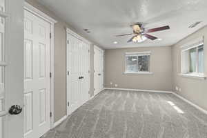 Unfurnished bedroom with visible vents, multiple closets, baseboards, and multiple windows