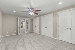 Unfurnished bedroom featuring french doors, baseboards, carpet floors, and two closets