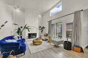 Living room with light wood-style floors, vaulted ceiling, large windows, and a fireplace