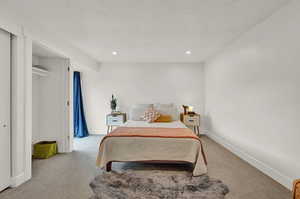 Bedroom with  ensuite bathroom, light colored carpet, and canned lights