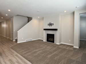 Unfurnished living room featuring hardwood / wood-style flooring and a tiled fireplace