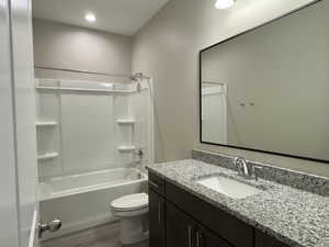 Full bathroom featuring washtub / shower combination, wood-type flooring, toilet, and vanity