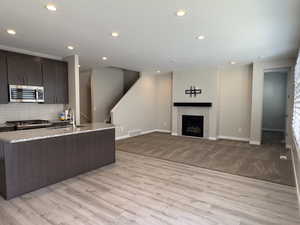 Kitchen with light hardwood / wood-style floors, sink, tasteful backsplash, and a tile fireplace