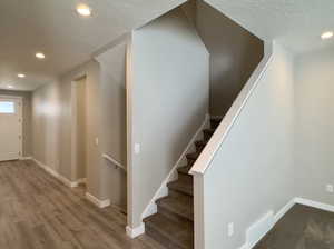 Staircase with a textured ceiling and hardwood / wood-style floors