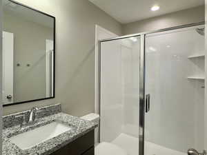 Bathroom with an enclosed shower, vanity, and toilet