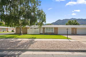 Single story home with a mountain view, a garage, and a front yard