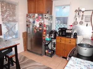 Kitchen featuring light tile patterned flooring and stainless steel refrigerator with ice dispenser