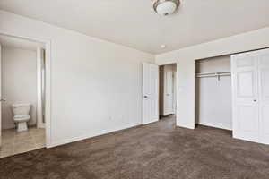 Unfurnished bedroom featuring carpet, a closet, and ensuite bathroom