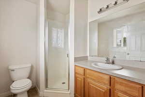 Bathroom featuring a shower with shower door, toilet, vanity, and tile patterned floors