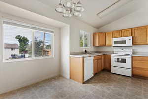 Kitchen featuring white appliances, lofted ceiling, an inviting chandelier, and light tile patterned floors