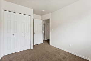 Unfurnished bedroom featuring a closet and dark carpet