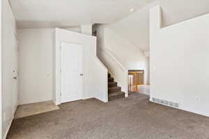 Interior space featuring carpet and high vaulted ceiling