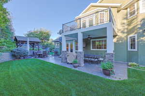 Rear view of house featuring a balcony, a patio area, an outdoor hangout area, a yard, and ceiling fan