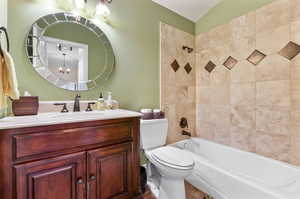 Full bathroom with toilet, tile patterned flooring, vanity, a notable chandelier, and tiled shower / bath combo