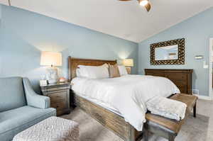 Carpeted bedroom with ceiling fan and lofted ceiling