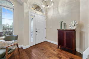 Entrance foyer featuring a wealth of natural light, an inviting chandelier, and dark wood-type flooring