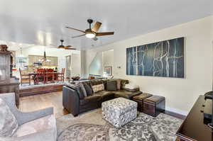 Living room featuring hardwood / wood-style floors and ceiling fan with notable chandelier