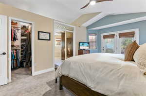 Carpeted bedroom featuring ceiling fan, a walk in closet, french doors, access to exterior, and lofted ceiling