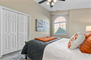 Carpeted bedroom featuring ceiling fan and a closet