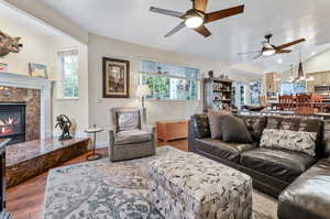 Living room with ceiling fan, plenty of natural light, light hardwood / wood-style flooring, and a high end fireplace