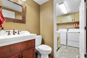 Bathroom featuring toilet, independent washer and dryer, tile patterned floors, and vanity