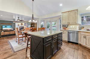 Kitchen featuring light wood-type flooring, tasteful backsplash, a kitchen island, dishwasher, and ceiling fan