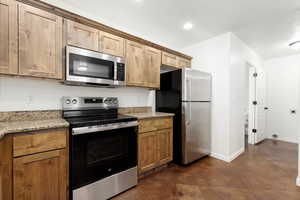 Kitchen featuring appliances with stainless steel finishes, and light stone counters