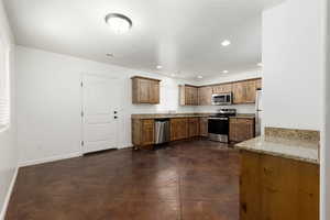 Kitchen featuring stainless steel appliances, sink, and light stone counters