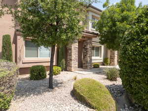 Front entrance of home with stucco, stone, sidewalk, rocks and trees