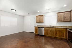 Kitchen with sink, light stone counters, and dishwasher