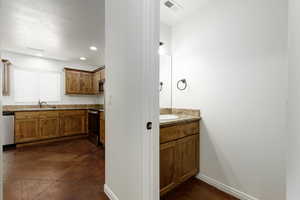 View 1/2 bathroom with light granite counter top and light brown cabinet off hallway