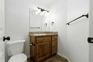 Bathroom 2 featuring white painted walls, vinyl, tile looking, patterned floors, vanity, and toilet