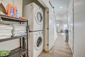 Laundry room featuring stacked washing maching and dryer and light wood-type flooring