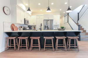 Kitchen featuring backsplash, appliances with stainless steel finishes, kitchen peninsula, and light wood-type flooring