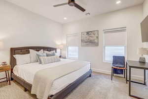 Carpeted bedroom featuring ceiling fan and multiple windows