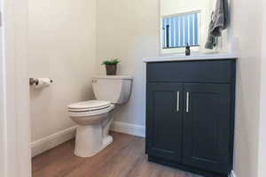 Bathroom with wood-type flooring, toilet, and vanity