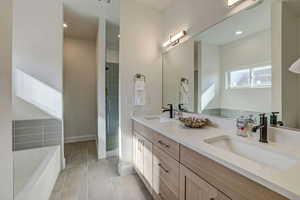 Bathroom with tile patterned flooring, independent shower and bath, and vanity