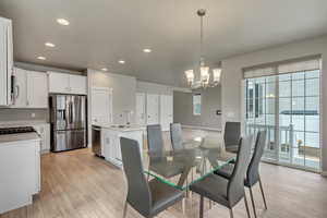 Dining room with light wood-type flooring, a wealth of natural light, sink, and a chandelier