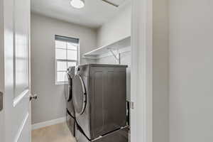 Laundry area with light hardwood / wood-style floors and separate washer and dryer